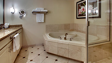 hotel bathroom with vanity, jacuzzi tub, shower